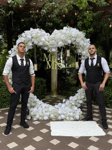 Bartenders beside a wedding flower arch